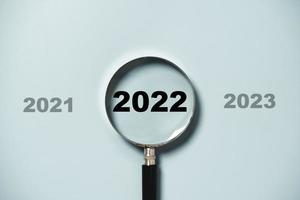 2022 anos dentro do vidro da lupa em fundo azul para foco no alvo de novos negócios de iniciar o conceito de ano novo. foto