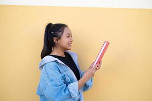 jovem estudante feliz com livro rosa sobre fundo marrom.