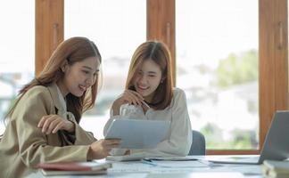 duas bela jovem empresária asiática trabalhando juntos usando tablet digital no escritório.