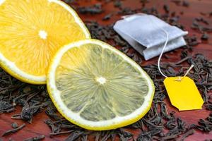 um limão suculento cortado encontra-se nas folhas de chá preto com um saquinho de chá foto