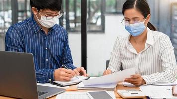 grupo de empresários asiáticos de trabalho em equipe usando máscara facial protetora no escritório durante pandemia de coronavírus covid-19, novo conceito de distanciamento normal e social foto
