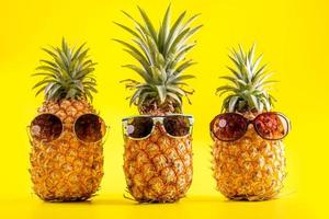 abacaxi criativo olhando para cima com óculos de sol e concha isolada em fundo amarelo, padrão de design de ideia de praia de férias de verão, espaço de cópia close-up foto