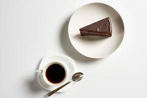 fatia de bolo de chocolate com caneca de café no fundo branco