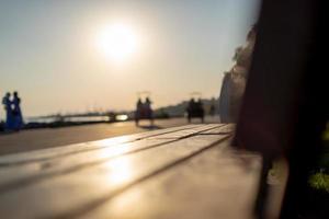 banco de madeira no parque e silhuetas de pessoas com luz solar foto