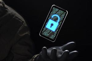 close-up iluminar o ícone de desbloqueio com código binário verde na tela do smartphone flutuando acima da mão do hacker na luva preta sobre fundo escuro, hacking e conceito de crime cibernético na internet foto