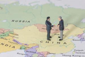 aperto de mão de dois empresários em miniatura no mapa da china foto