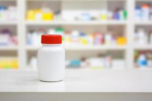 frasco de remédio branco em branco no balcão com prateleiras desfocadas de drogas na farmácia foto