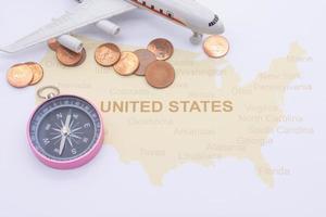 bússola de passaporte e moedas em um mapa americano. conceito de viagens de negócios