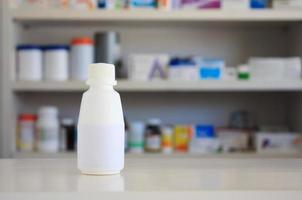 rótulo branco em branco do frasco de remédio com prateleiras desfocadas de drogas no fundo da farmácia foto