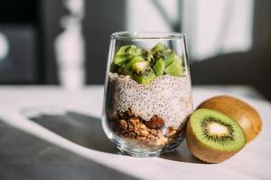 café da manhã saudável. pudim de chia com kiwi e granola em vidro foto