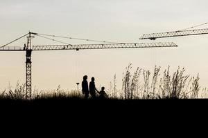 guindastes de construção industrial e silhuetas de construção sobre o sol ao nascer do sol foto