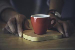 barista deu a xícara de café vermelha na bandeja em frente ao bar. foto