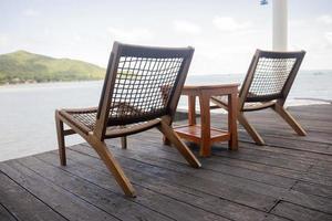 cadeiras de madeira com móveis no terraço à beira-mar. foto