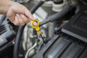 a mão da mulher está verificando o motor, abra o capô. foto