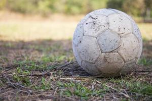 bola de futebol velha no campo de grama foto