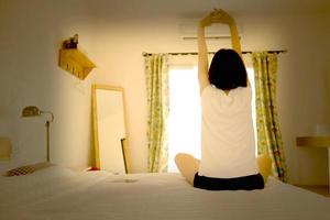 mulher esticando em sua cama, vista traseira foto