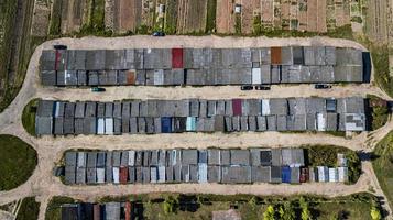 vista aérea da garagem do apartamento com estacionamento coberto, carros e árvores verdes de prédio residencial de vários andares no início da manhã. infraestrutura urbana e conceito de transporte. vista panorâmica. foto