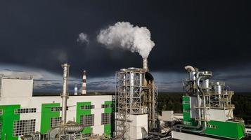 fumaça branca de chaminés de fábrica contra um céu escuro foto