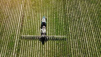 vista aérea do pulverizador agrícola trabalhando no campo verde em um dia ensolarado foto
