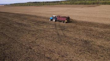 trator espalha estrume no campo fotografia aérea de um drone foto