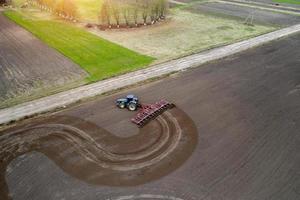 trator cultivando campo na primavera, vista aérea foto