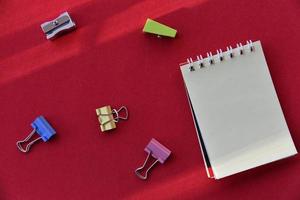 perfurador de lápis e bloco de notas em um fundo vermelho foto