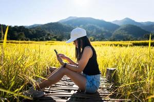 mulher adulta viajante solo usa smartphone no campo de arroz. foto