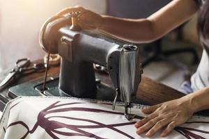 mulher com tecido na máquina de costura vintage foto