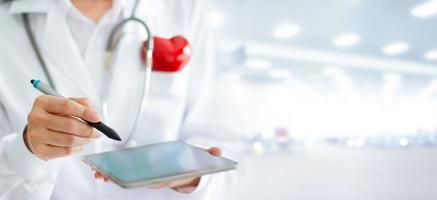 médico com forma de coração vermelho e estetoscópio usando tablet digital no conceito de hospital, saúde e medicina foto