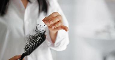 mulher perdendo cabelo na escova de cabelo na mão, foco suave foto