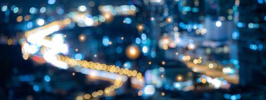 fundo desfocado abstrato da luz da cidade com bokeh noturno, paisagem urbana em banner panorâmico para uso na parede de pano de fundo no conceito de centro de negócios moderno, luz de carro e tráfego na estrada foto