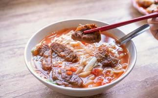 macarrão de carne - taiwan ramen refeição com caldo de molho de tomate na tigela na mesa de madeira brilhante, famosa comida de estilo chinês, close-up, vista superior, copie o espaço foto