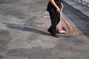 limpador varre o lixo na grande área ao ar livre de asfalto ao meio-dia. foto