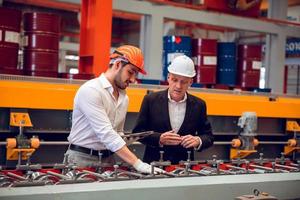 capataz operário e gerente de engenharia trabalhando juntos no local de trabalho industrial, usando capacete para segurança foto