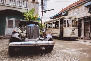 carro antigo estacionado em frente ao antigo hotel com vagabundo passando na rua. yogyakarta, indonésia-março, 2022 foto