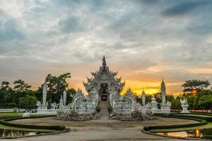 pôr do sol no templo branco conhecido como wat rong khun na província de chiang rai da tailândia. foto