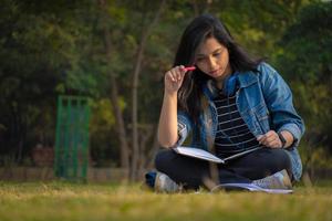 estudante indiano na imagem em tamanho real do campus da faculdade lendo livros e assistindo a câmera foto