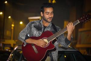 homem com guitarra vermelha e tocando sua guitarra foto