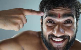 homem indiano pandit mostrando tika na cabeça e feliz foto