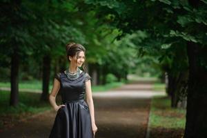 jovem e bela mulher posando em um vestido preto em um parque. foto