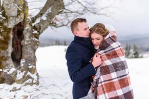 o noivo leva sua noiva pela mão para uma velha faia solitária. casamento de inverno. lugar para um logotipo. foto