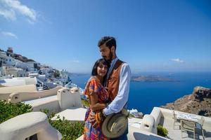 um homem e uma mulher estão se abraçando contra o pano de fundo do rock skaros na ilha de santorini. a aldeia de Imerovigli. foto