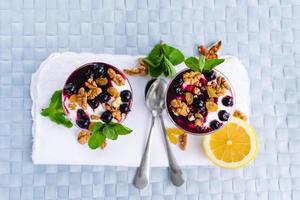 sobremesa de creme com frutas vermelhas, geleia de groselha preta e nozes decoradas com folhas de hortelã foto