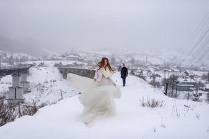 o noivo leva sua noiva pela mão para uma velha faia solitária. casamento de inverno. lugar para um logotipo. foto