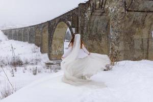 o noivo leva sua noiva pela mão para uma velha faia solitária. casamento de inverno. lugar para um logotipo. foto