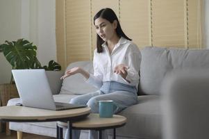 bela jovem fazendo videoconferência via computador em casa, conceito de tecnologia de negócios foto