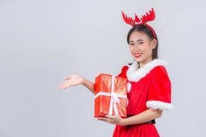 menina asiática no vestido de natal segurando a caixa de presente no fundo branco foto