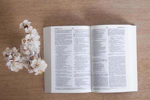 abra a bíblia sagrada na vista de mesa com galho de primavera florescendo. foco variativo foto