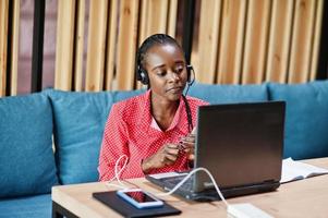 mulher afro-americana trabalha em um operador de call center e agente de atendimento ao cliente usando fones de ouvido de microfone trabalhando no laptop. foto