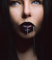 retrato de mulher de cabelo escuro com lábios escuros com cruz na boca